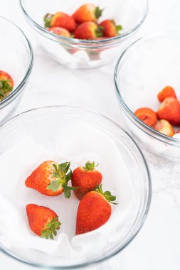 Taze yıkanmış ve kurutulmuş çilekler kağıt havluyla kaplı cam bir kasede dikkatlice düzenlenir. Atıştırmaya ya da daha fazla kullanılmaya hazır hale getirilir..