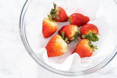 Taze yıkanmış ve kurutulmuş çilekler kağıt havluyla kaplı cam bir kasede dikkatlice düzenlenir. Atıştırmaya ya da daha fazla kullanılmaya hazır hale getirilir..