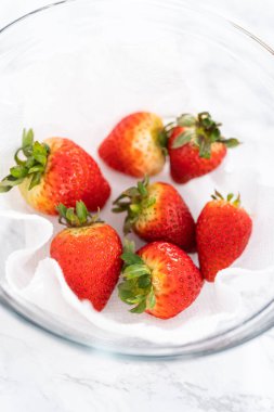 Taze yıkanmış ve kurutulmuş çilekler kağıt havluyla kaplı cam bir kasede dikkatlice düzenlenir. Atıştırmaya ya da daha fazla kullanılmaya hazır hale getirilir..