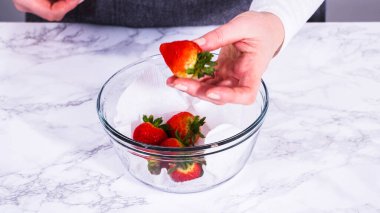 Çilekler, yeni yıkanmış ve kurutulmuş, cam bir kasede güzelce depolanmış kağıt havluyla kaplanmış ve tazeliği korumak için plastikle kaplanmış..