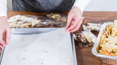 Beyaz kremalı kurabiyelerle dolu bayramlık zencefilli sandviç kurabiyelerinin yukarıdan görünüşü, çeşitli kesme kurabiyelerin olduğu tepsilerin yanında metal bir tepside düzgünce dizilmiş. Sahne tatil ruhunu yakalıyor.