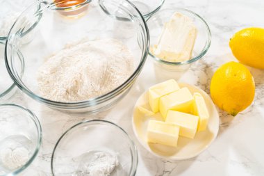 Tereyağlı küp tereyağı, taze limon, yumurta, şeker ve vanilya özü içeren cam kaselerde düzgünce sıralanmış bir fırın malzemeleri koleksiyonu. Bu yüksek kaliteli hazırlık çekimi...