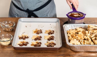 Çikolataya batırılmış ve fındık ezmesi ile süslenmiş kar tanesi şeklindeki kesme şekerli kurabiyeler yaratmak. Parşömen üzerinde zarif bir şekilde sunulmuş..