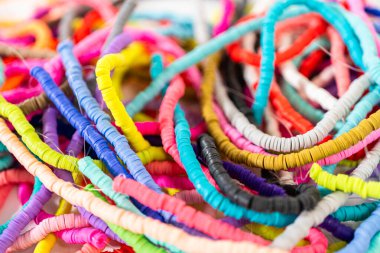 Beyaz bir masadaki renklere göre düzenlenmiş canlı bir kil boncuk koleksiyonu genç zanaatkarlara kendi eşsiz bileziklerini yapmaları için ilham vermeye hazır..