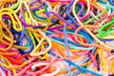 Beyaz bir masadaki renklere göre düzenlenmiş canlı bir kil boncuk koleksiyonu genç zanaatkarlara kendi eşsiz bileziklerini yapmaları için ilham vermeye hazır..