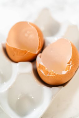 Çikolata Ginger Şekerli Kurabiye Hamur tarifinde kullanılan yumurta kalıntılarını gösteren iki kırık yumurta kabuğunun yakın çekimi, pişirme sürecini sembolize ediyor..