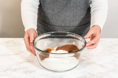 Elinde un ve kakao tozu dolu bir karıştırma kabı tutan birinin ön görüntüsü. Çikolata zencefilli, şekerli kurabiye hamuru, ıslak malzemelere karıştırılmaya hazır..