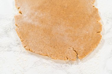 Kehribarlı kurabiye hamurunun yukarıdan görünüşü geniş, ince, eşit düzleştirilmiş bir katmana sarılmış, hafifçe kavrulmuş mermer bir yüzeyde şekillendirilmeye hazır..