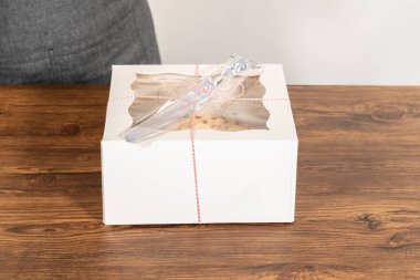 Tuzlu karamel şekerlemeleri ve zencefilli ekmek parçacıklarıyla süslenmiş zencefilli keki dikkatlice hediye etmek için açık pencereli beyaz bir kağıt bohça kek kutusuna yerleştiriyorum..