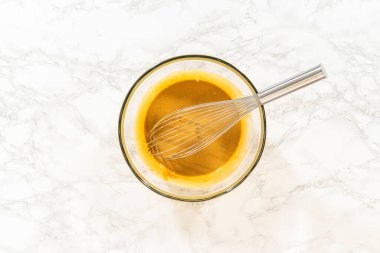 İçinde yumurta, pekmez ve ekşi krema olan cam bir kase çikolatalı zencefilli kek için karıştırılmaya hazır..