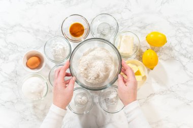 Resim, un, şeker, tereyağı, yumurta ve fırınlanmaya hazır taze limonlar da dahil olmak üzere Lemon Spritz Kurabiyeleri 'nin malzemelerini gösteriyor..