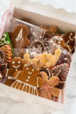 Kapalı bir perspektiften yakalanan açık bir Noel kurabiyesi hediye kutusu, içinde gülümseyen zencefilli kurabiye figürleri ve yıldızların da bulunduğu çok güzel düzenlenmiş zencefilli kurabiye kurabiyelerini gözler önüne seriyor.