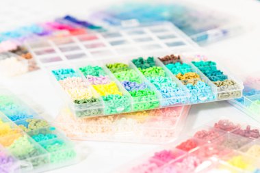 Beyaz bir masaya yerleştirilmiş çeşitli kil boncuk kutuları yaratıcı çocukların el sanatları projesini bekliyor..