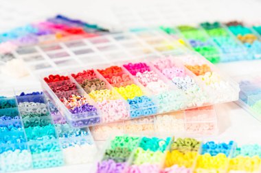 Beyaz bir masaya yerleştirilmiş çeşitli kil boncuk kutuları yaratıcı çocukların el sanatları projesini bekliyor..