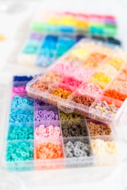 Beyaz bir masaya yerleştirilmiş çeşitli kil boncuk kutuları yaratıcı çocukların el sanatları projesini bekliyor..