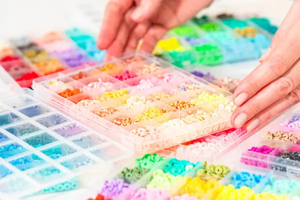 Beyaz bir masaya yerleştirilmiş çeşitli kil boncuk kutuları yaratıcı çocukların el sanatları projesini bekliyor..