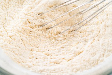 Klasik Şekerli Kurabiye Hamuru, un ve şeker de dahil olmak üzere kuru malzemelerin yakın çekim görüntüsü kasede dokulu bir karışım gösteriyor. Bu makro atış un dokusunun ince detaylarını yakalar.