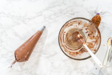 Düz yatıyordu. Çikolata kreması özenle bir torbaya aktarılıyor. Lezzetli kekleri süslemeye hazır..