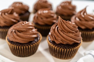 Taze pişmiş kekler ustaca zengin karamel ile dolduruldu ve kadife çikolatalı şekerlemeyle süslendi. Hepsi de el değmemiş beyaz servis tabağında zarif bir şekilde sunuldu..