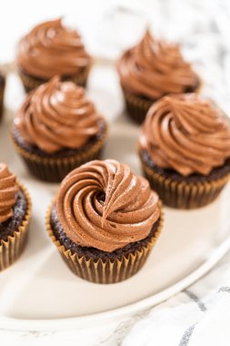 Taze pişmiş kekler ustaca zengin karamel ile dolduruldu ve kadife çikolatalı şekerlemeyle süslendi. Hepsi de el değmemiş beyaz servis tabağında zarif bir şekilde sunuldu..