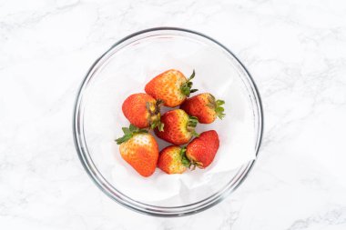 Taze yıkanmış ve kurutulmuş çilekler kağıt havluyla kaplı cam bir kasede dikkatlice düzenlenir. Atıştırmaya ya da daha fazla kullanılmaya hazır hale getirilir..