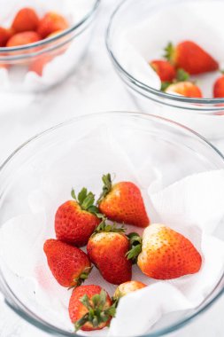 Taze yıkanmış ve kurutulmuş çilekler kağıt havluyla kaplı cam bir kasede dikkatlice düzenlenir. Atıştırmaya ya da daha fazla kullanılmaya hazır hale getirilir..