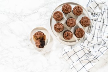 Düz yatıyordu. Taze pişmiş kekler ustaca zengin karamel ile dolduruldu ve kadife çikolatalı şekerlemeyle süslendi. Hepsi de el değmemiş beyaz servis tabağında zarif bir şekilde sunuldu..