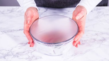 Çilekler, yeni yıkanmış ve kurutulmuş, cam bir kasede güzelce depolanmış kağıt havluyla kaplanmış ve tazeliği korumak için plastikle kaplanmış..