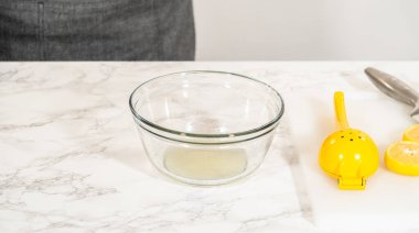 Bıçak ve limon aromalı dilimleme tahtasına yerleştirilmiş bir limon. Bu adım kurabiyelere taze limon aroması eklemek için gereklidir..