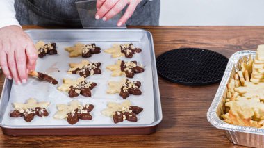 Dikkatlice paketlenmiş Noel kurabiyeleri, çikolataya batırılmış ve şeffaf selofan ambalajla sunulmuş, bayram hediyesi olarak mükemmel..