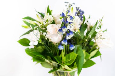 Taze beyaz güllerin ve çeşitli çiçeklerin bulunduğu büyüleyici bir buket, zarif bir vazoda düzenlenmiş, zamansız bir güzellik yayıyor..