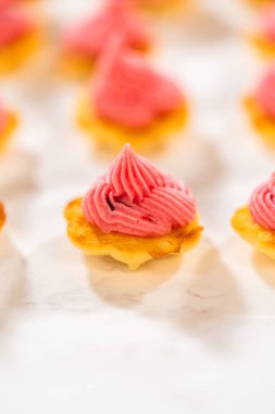 Üstünde kızılcık kreması olan taze pişmiş limonlu spritz kurabiyeler. Canlı pembe dolgu, altın kurabiye tabanıyla çok güzel tezat oluşturuyor. Zarif bir tatlı oluşturuyor.