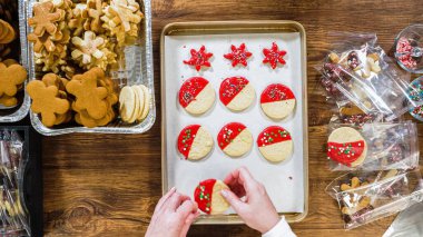 Düz yatıyordu. Dikkatlice paketlenmiş Noel kurabiyeleri, çikolataya batırılmış, ezilmiş fındık serpiştirilmiş, ve şeffaf selofan ambalajla sunulmuş..