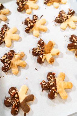 Çikolataya batırılmış ve fındık ezmesi ile süslenmiş kar tanesi şeklindeki kesme şekerli kurabiyeler yaratmak. Parşömen üzerinde zarif bir şekilde sunulmuş..