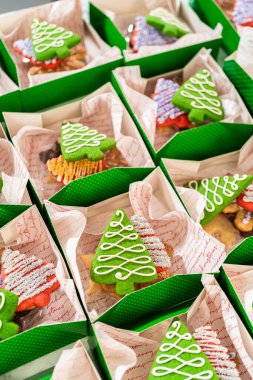 Yakın plan bir perspektiften yakalanan yeşil tatil hediye kutuları süslenmiş Noel kurabiyeleriyle dolu parşömen kağıdıyla güzelce düzenlenir. Festivalde eldiven, ağaç ve yıldız çeşitleri yer alıyor.