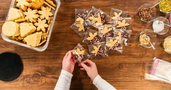 Dikkatlice paketlenmiş Noel kurabiyeleri, çikolataya batırılmış ve şeffaf selofan ambalajla sunulmuş, bayram hediyesi olarak mükemmel..