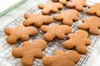 Soğutma rafına yerleştirilmiş taze pişmiş zencefilli kurabiye tepsisinin yakından görüntüsü, şenlik ayrıntılarını vurguluyor..