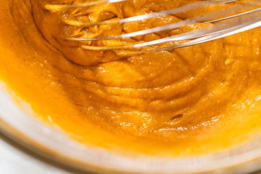 Ağız sulandırıcı ev yapımı balkabağı pastası için büyük bir karıştırma kabında ustalıkla harmanlanmış malzemelerin yakın çekimi..