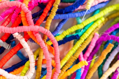 Beyaz bir masadaki renklere göre düzenlenmiş canlı bir kil boncuk koleksiyonu genç zanaatkarlara kendi eşsiz bileziklerini yapmaları için ilham vermeye hazır..