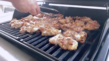 Salamura edilmiş tavuk butları küçük bir Weber ızgarasının ızgarasında cızırdar, havayı iştah açıcı bir koku ve hafif bir dumanla doldurur..