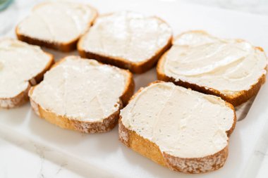 Adım adım küçük salatalıklı sandviçler, dilimlenmiş beyaz ekmek, krem peyniri ve ince dilimlenmiş salatalıklar. Parti aperatifleri, öğleden sonra çayı ya da gelin partisi için ideal.