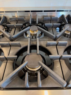 Temiz siyah diş minesi ve görünür pirinç halkalarla dökme demir gaz ocağı ızgaralarının detaylı görüntüsü. Cihaz özellikleri, mutfak ekipmanları veya pişirme teknikleri için kullanışlı.