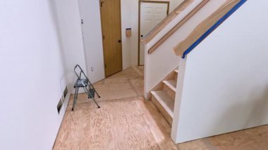 Süpürge, Colorado, ABD-12 Mayıs 2024-Ağır çekim-A merdiveni koruma amaçlı koruyucu örtüler ve maskeleme bantlarıyla yenilenen bir evde. Bölge boyamaya hazır.