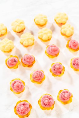 Üstünde kızılcık kreması olan taze pişmiş limonlu spritz kurabiyeler. Canlı pembe dolgu, altın kurabiye tabanıyla çok güzel tezat oluşturuyor. Zarif bir tatlı oluşturuyor.