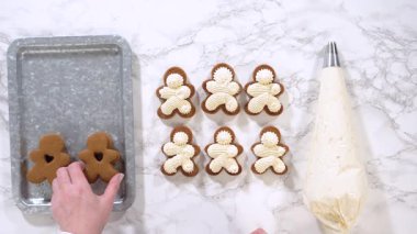 Düz yatıyordu. Zencefilli kurabiyeler mermer yüzeyde ikinci yarılarını beklerler, her biri lezzetli sandviçler yapmak için tereyağlı kremayla titizlikle borular. Boruların hassasiyeti şenlik katıyor.