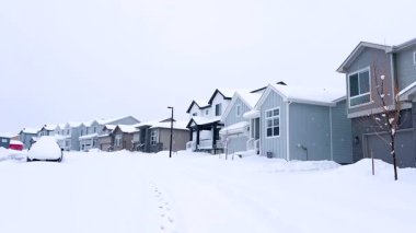 Castle Rock, Colorado, ABD-14 Mart 2024-Ağır çekim sahnesi, karla kaplanmış bir cadde boyunca uzanan ve kış boyunca uzanan berrak bir patikayla noktalanmış evlerle banliyö sükunetini tasvir ediyor.