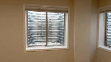 Süpürge, CO, USA-196 - 08 Aralık 2024 - Temiz bir bodrum penceresi pürüzsüz beyaz dekoratif taşlarla doludur. Metal duvarlardan ve camdan yansıyan doğal ışık,