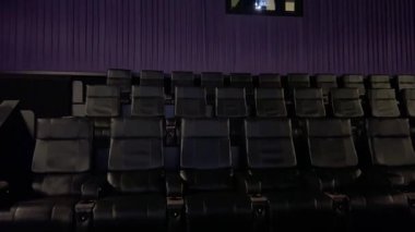 Colorado Springs, CO, USA-074 - 20 Haziran 2024 - Boş modern bir sinema salonunda geniş ve yakın çekim serisi Sıralar halinde sıralanmış deri koltuklar ve mor duvarlar. Yazı işleri için ideal
