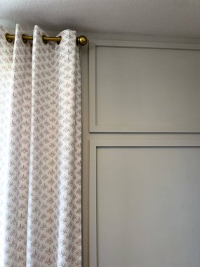 Şık pencere düzeninde desenli perdeler ve temiz beyaz panelli bir duvar var. Yenileme görselleri, gayrimenkul fotoğrafçılığı ya da stil rehberleri için harika..