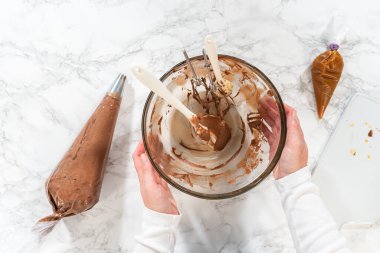 Düz yatıyordu. Çikolata kreması özenle bir torbaya aktarılıyor. Lezzetli kekleri süslemeye hazır..